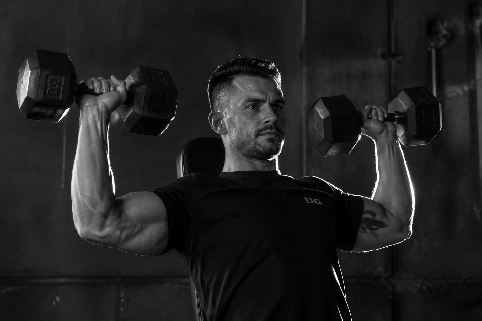 Dumbbell shoulder press in dark gym